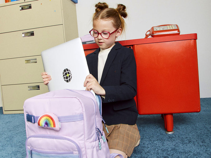 Student putting in laptop in the CALPAK Kids Backpack in pink lavender Orchid Pink backpack