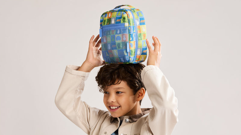 Child holding the CALPAK + Miffy Everything Cube in Blue Zoo Trip featuring blues, yellow, and green tiles with Miffy and animal characters