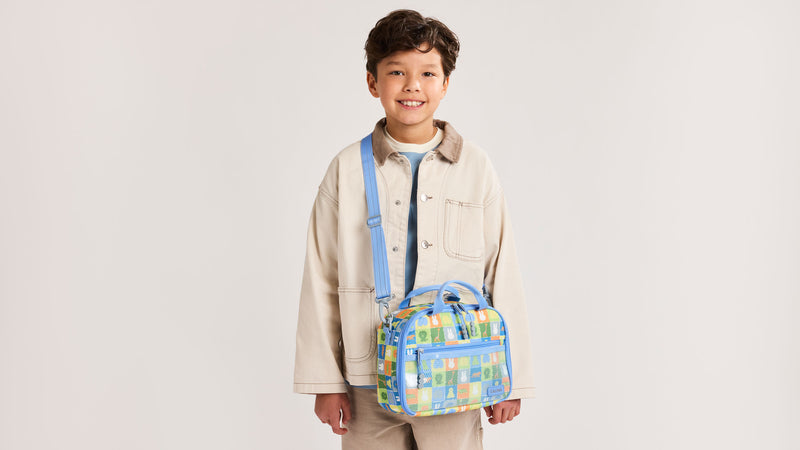 Boy with the Colorful CALPAK Kids Lunch Bag with Miffy and other animal characters, wearing as as crossbody 