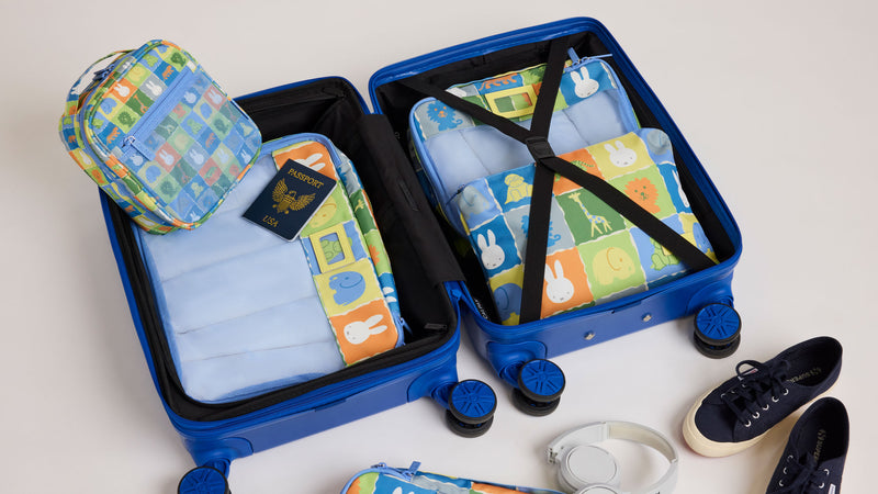 CALPAK + MIffy Packing Cubes set in Miffy Blue Zoo Trip with colorful tiles featuring Miffy and animal characters packed in a blue suitcase
