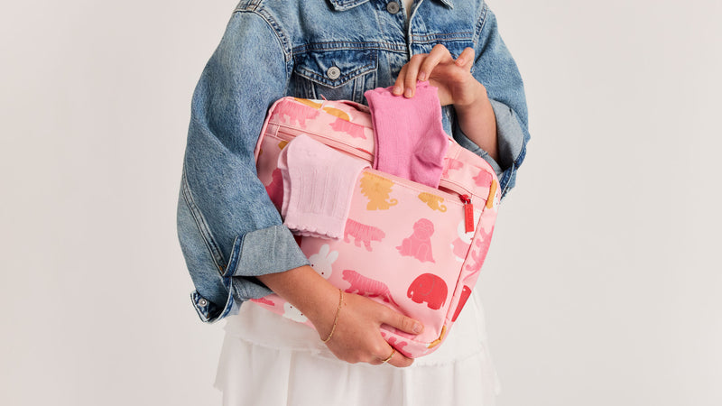 Child holding the CALPAK + Miffy Packing Cube Set in Pink Miffy Zoo Trip with zippered pockets 