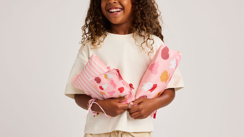 Child holding the CALPAK Compakt Zip Pouches in pink featuring Miffy 