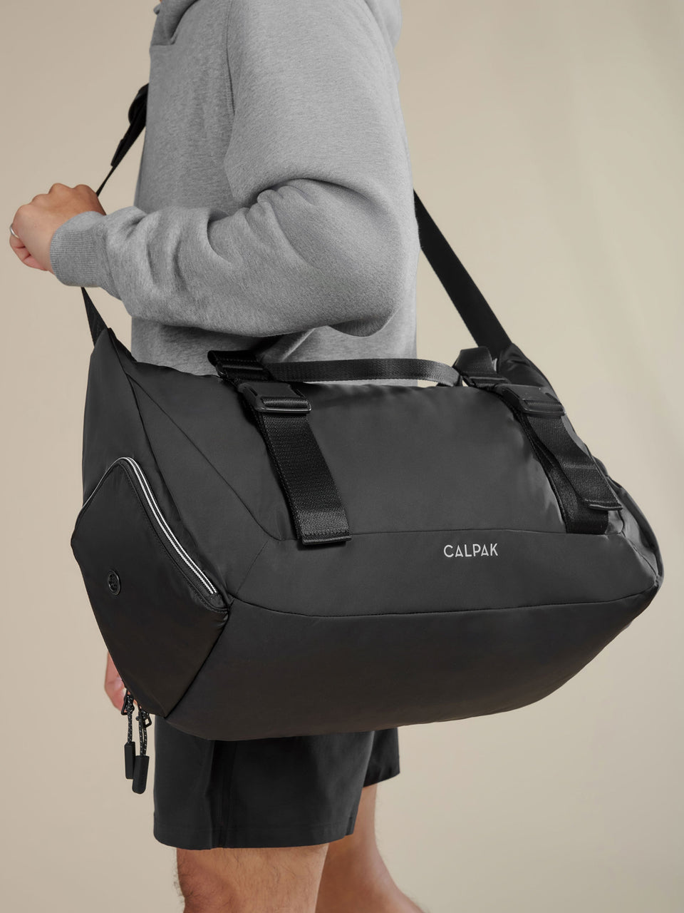 Model displaying CALPAK Fit Gym Bag with padded, adjustable shoulder strap and adjustable yoga mat straps in black; TBF2401-BLACK, BTBF2401-BLACK