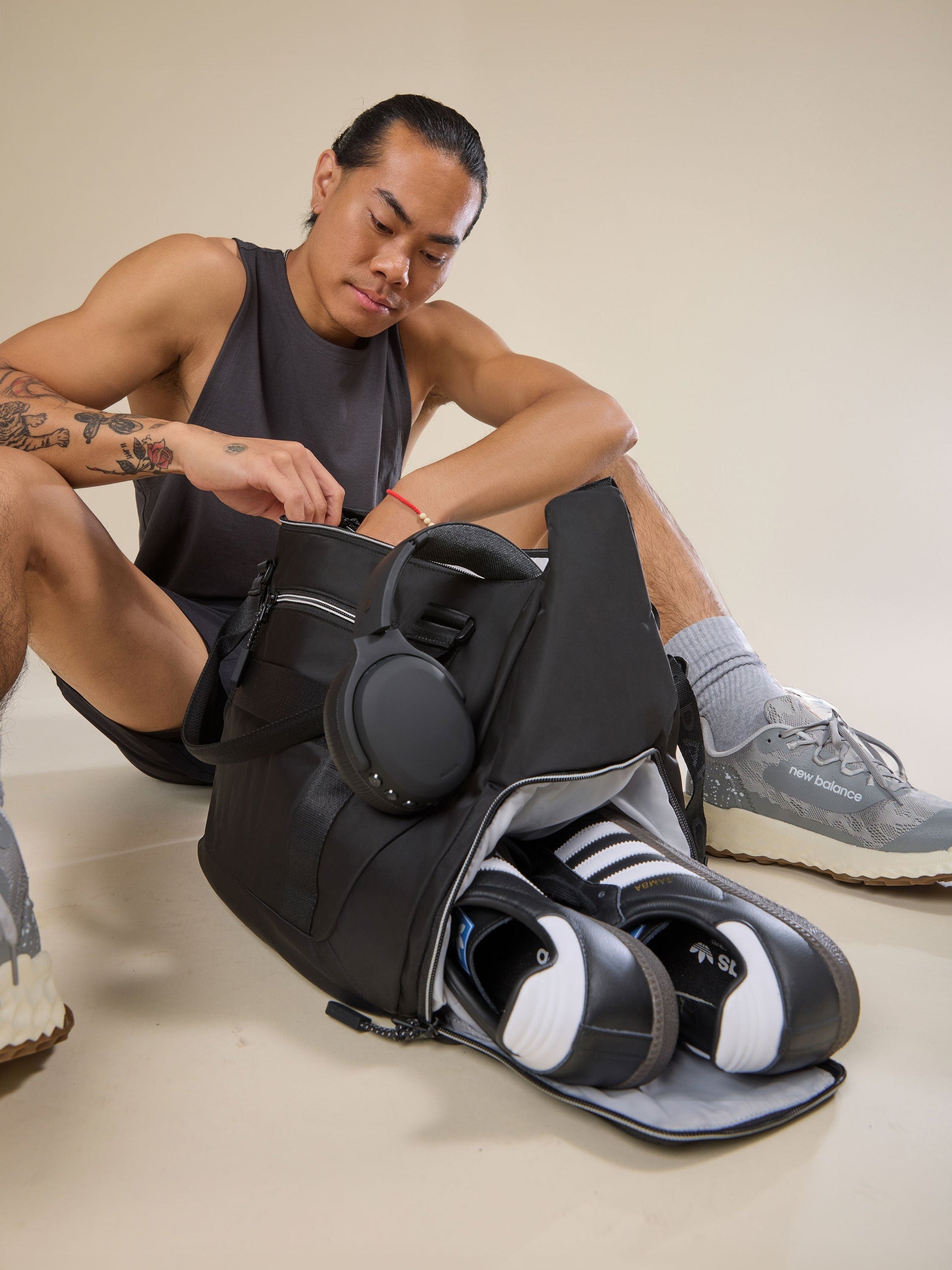 Model displaying separate shoe compartment of black CALPAK Fit Gym Bag; TBF2401-BLACK, BTBF2401-BLACK