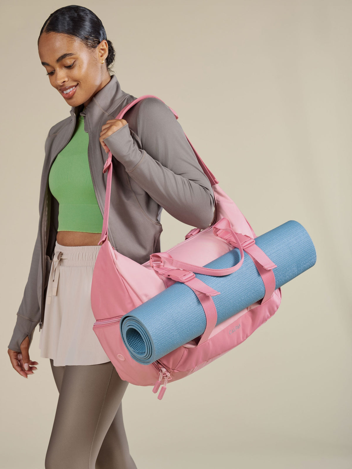 Model carrying Fit Gym Bag over shoulder with yoga mat secured to bag by the adjustable yoga mat straps on the exterior of the duffel; TBF2401-TEA-ROSE, BTBF2401-TEA-ROSE