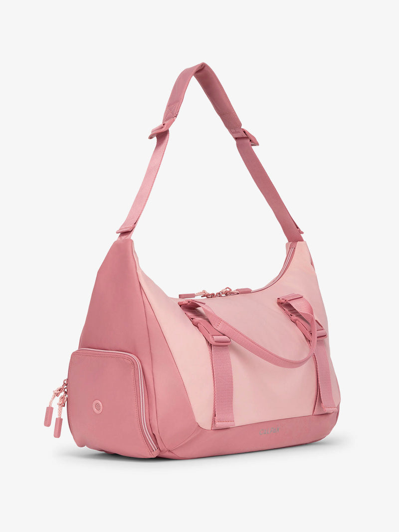 Side view of CALPAK Fit gym duffel bag with shoe compartment and adjustable yoga mat straps in pink tea rose