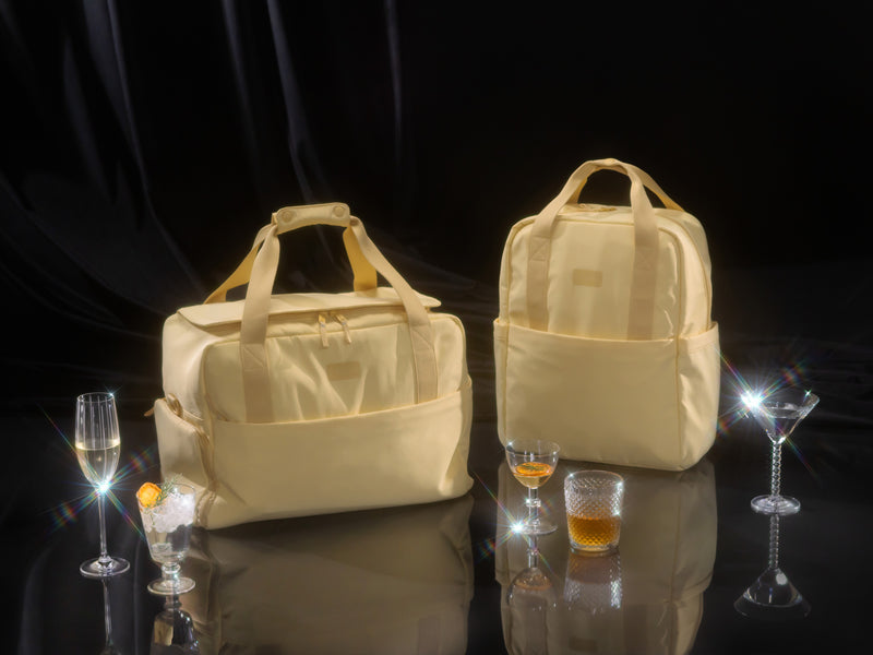 Elegant table setting with glassware and CALPAK Connect Laptop Duffel and Connect Laptop Backpack in Sunshine