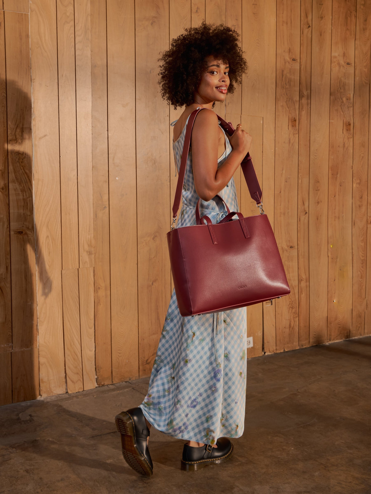 Model wears CALPAK Haven Laptop tote over shoulder displaying adjustable strap; ATO2101-CABERNET
