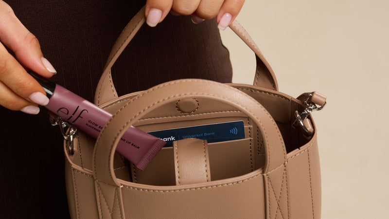Person holding brown Taupe Haven Mini Crossbody Bag with lip products inside