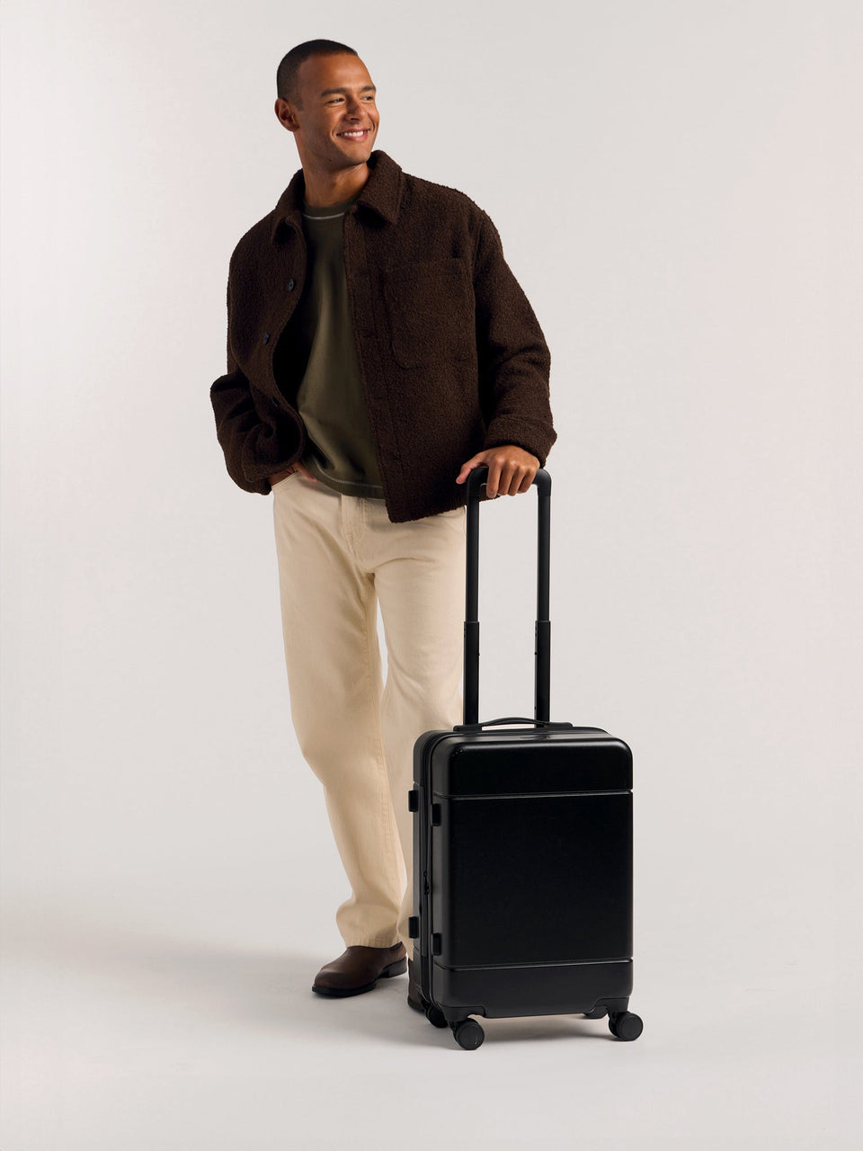 Model with CALPAK Hue hard shell rolling carry-on luggage in Black color; LHU1020-NP-BLACK