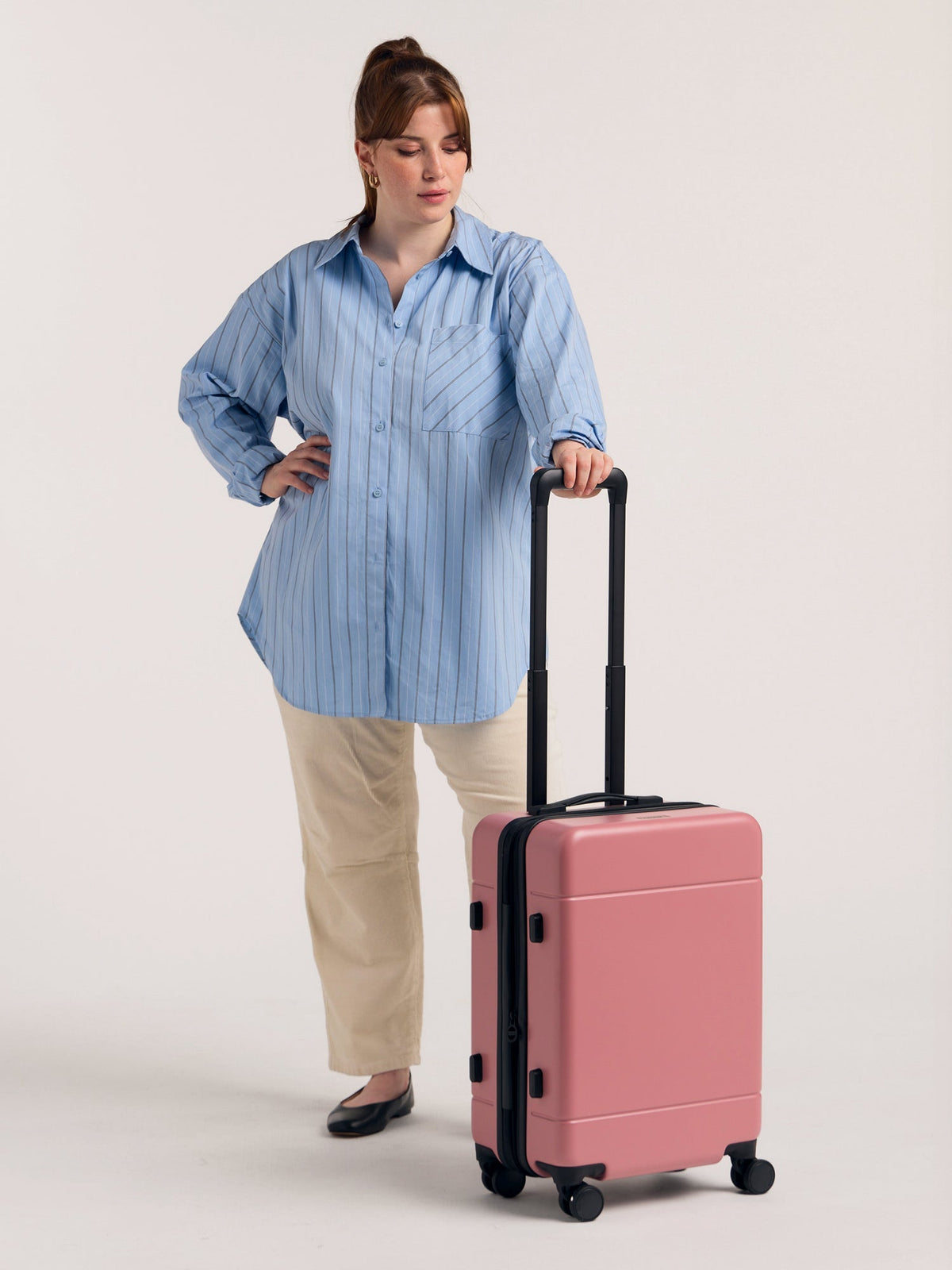 Model with CALPAK Hue hard shell rolling carry on luggage in light pink mauve; LHU1020-NP-MAUVE