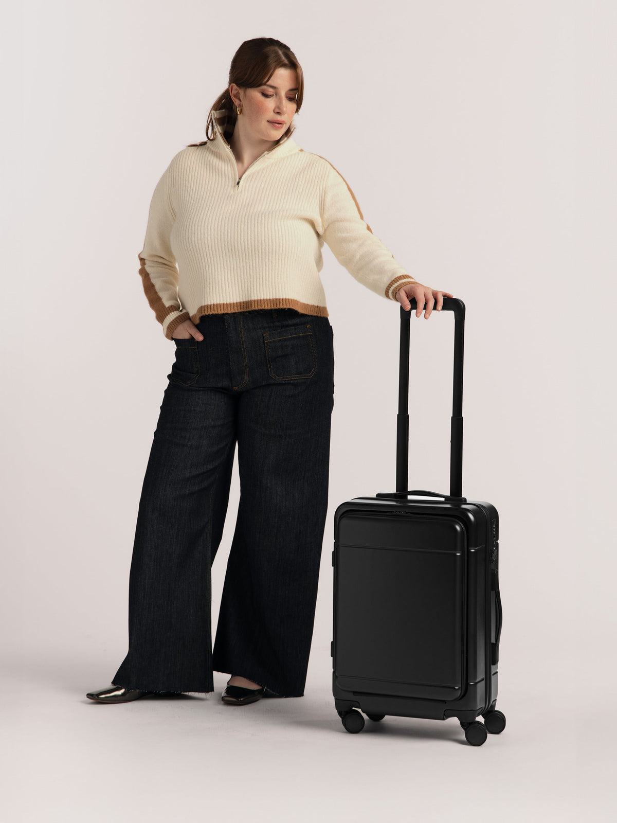 Model with CALPAK Hue Front Pocket Carry-On Luggage with hard shell carry-on spinner luggage with front-laptop compartment in Black; LHU1020-BLACK