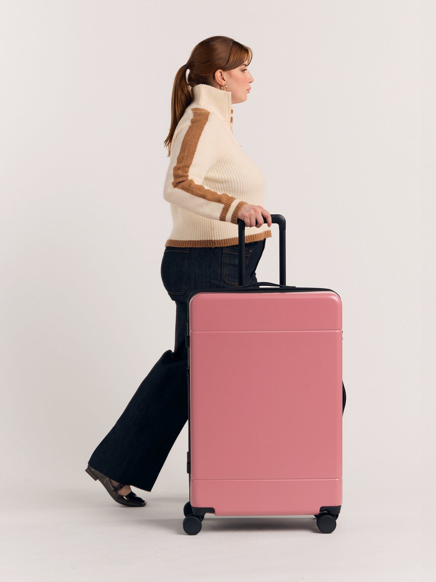 Model with CALPAK Hue large 30 inch hard shell luggage in pink Mauve; LHU1028-MAUVE