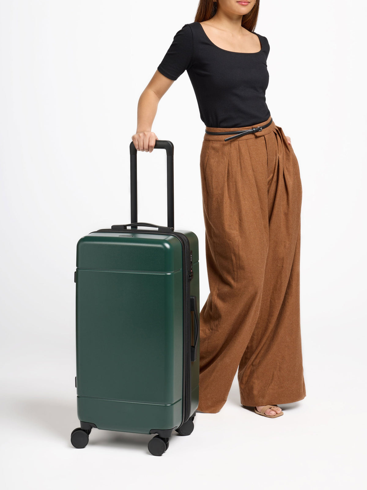 Model rolling 360 wheels of Hue Medium Trunk Luggage by CALPAK in emerald green; LHU1026-EMERALD
