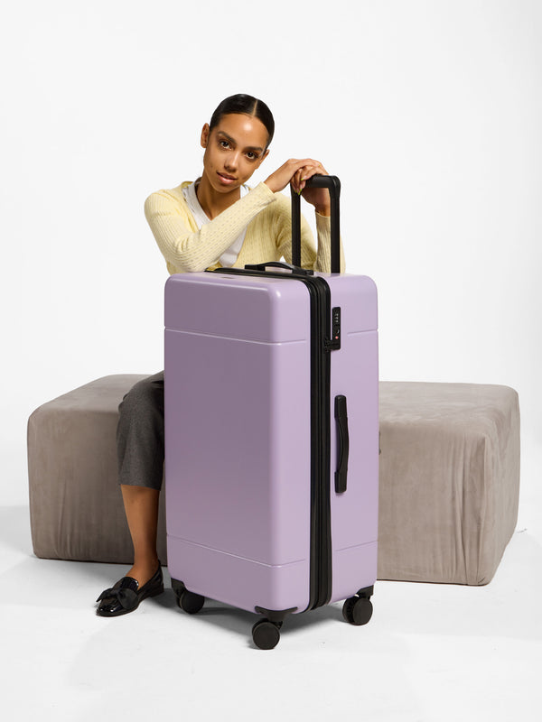 Model with CALPAK Hue Trunk Luggage in orchid