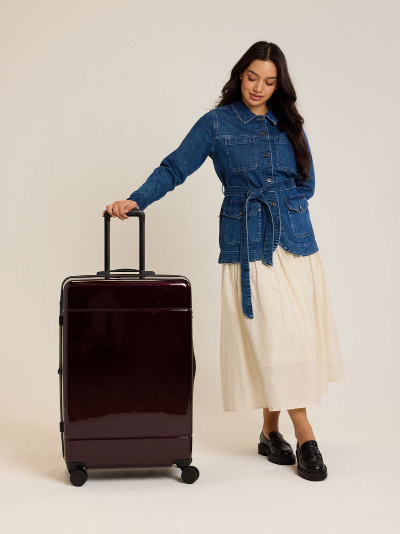 Model with CALPAK maroon Hue Large Luggage in Glazed Dark Cherry