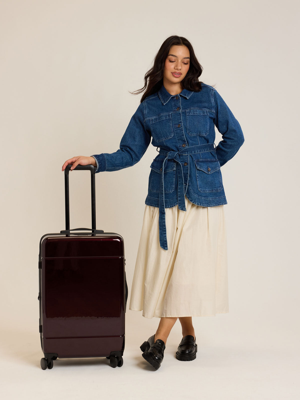 Model with CALPAK Hue Medium Luggage in maroon Glazed Dark Cherry; LHU1024-GLAZED-DARK-CHERRY
