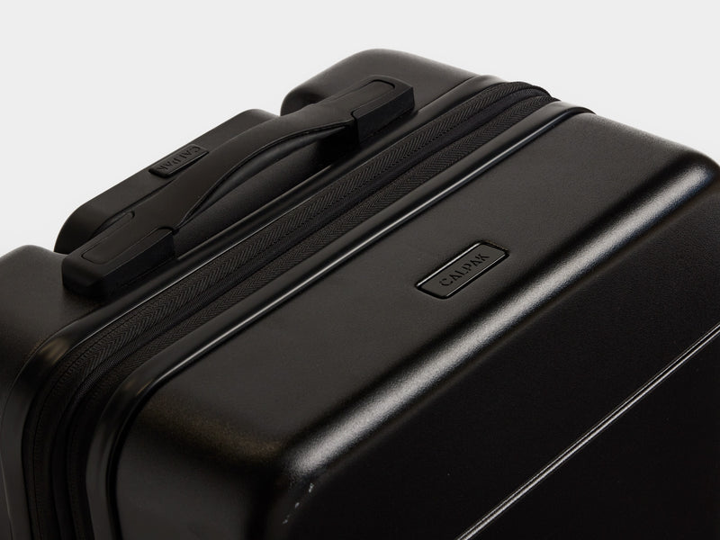 Closeup shot of top grab handle and logo on black CALPAK Hue Carry-On Luggage