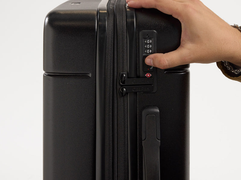 Model showing TSA-approved lock on black CALPAK Hue Carry-On luggage
