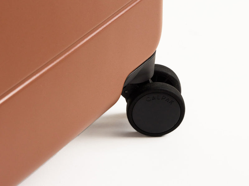 Closeup shot of 360-degree spinner wheel on CALPAK Hue Carry-On in brown