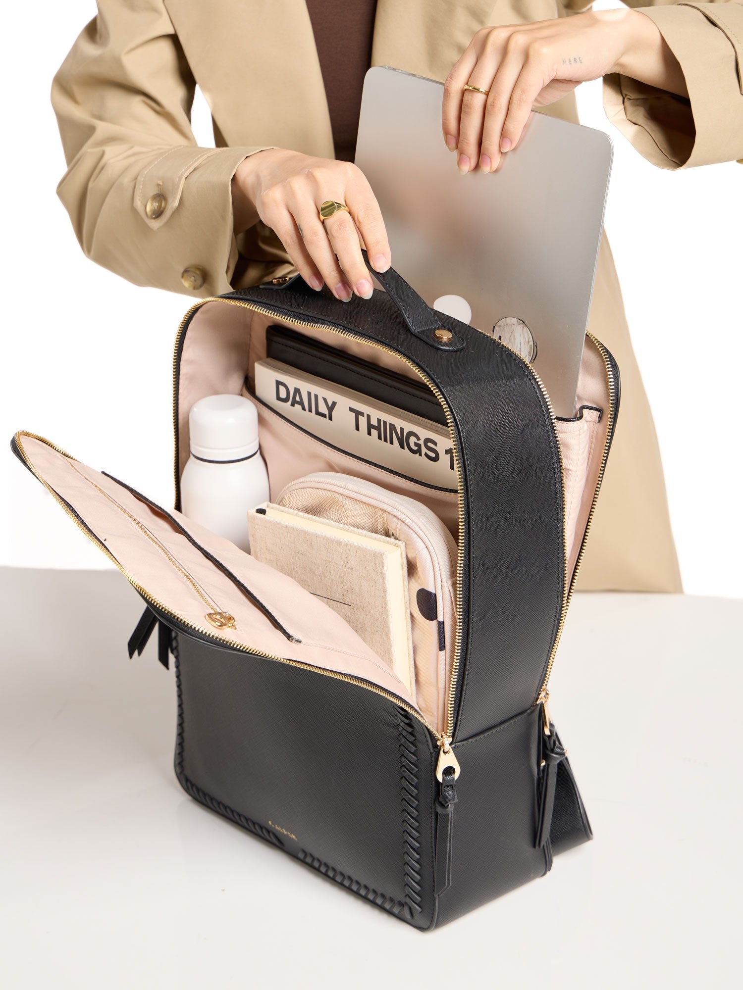 Model placing 17 inch laptop within laptop compartment of CALPAK laptop backpack in black