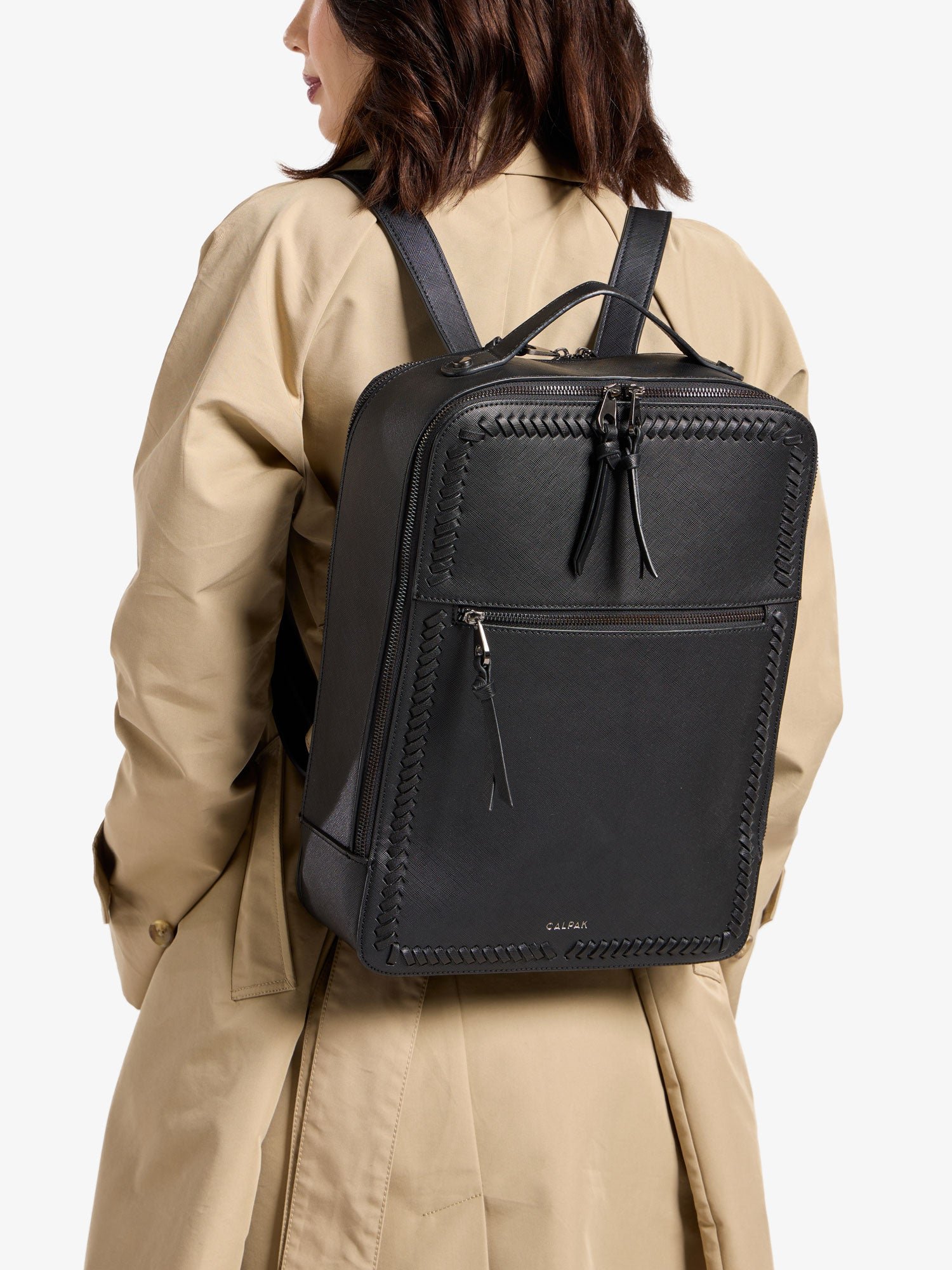 Model wearing gunmetal black CALPAK laptop backpack for 17 inch laptop