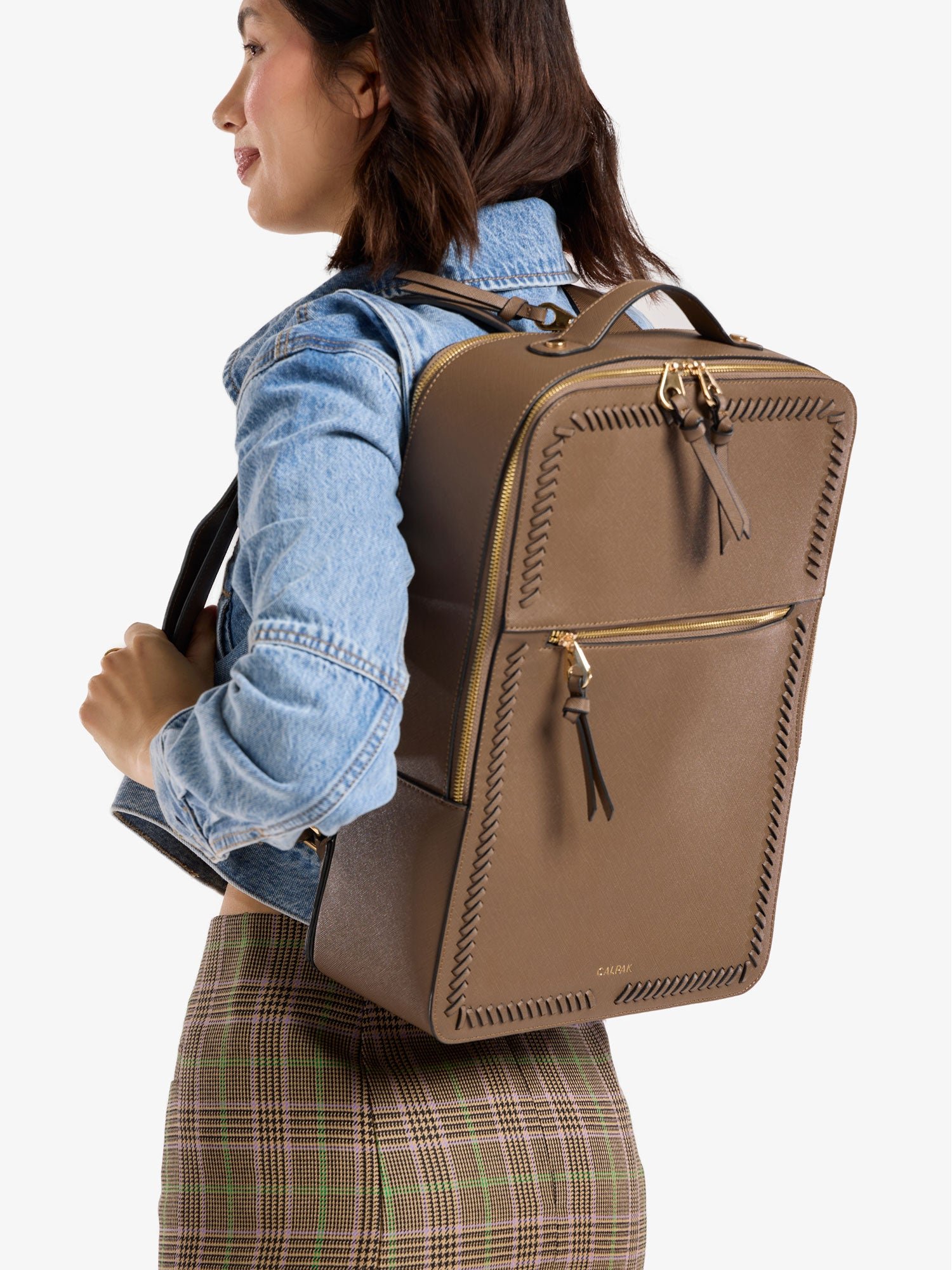 Model wearing brown CALPAK Kaya 17 inch Laptop Backpack
