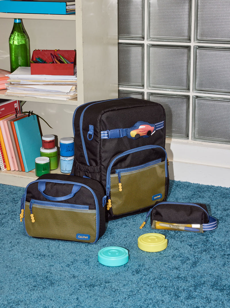 CALPAK Kids Collection Large Kids Backpack Bundle in Black that includes Kids Lunch Bag, Kids Pencil Case, red Car Pluffy Bag Charm, and Set of 2 Ice Packs in a kids room