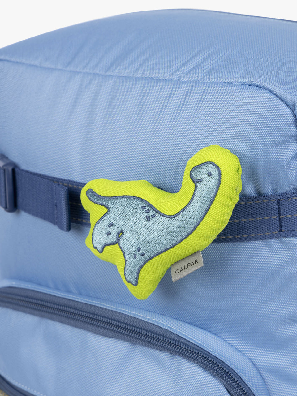 CALPAK Kids Collection blue and green Dinosaur Pluffy Bag Charm attached to Kids Large Blue Backpack; BCKM5000-BLUE