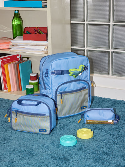 CALPAK Kids Collection Large Kids Backpack Bundle in Blue that includes Kids Lunch Bag, Kids Pencil Case, Rainbow Pluffy Bag Charm, and Set of 2 Ice Packs in a kid's room; BCKL2501-BLUE view 2