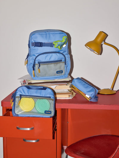 CALPAK Kids Collection Small Kids Backpack Bundle in Blue that includes Kids Lunch Bag, Kids Pencil Case, blue and green Dinosaur Pluffy Bag Charm, and Set of 2 Ice Packs in a kid's room; BCKS2501-BLUE view 2