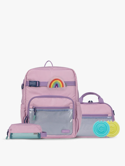 CALPAK Kids Collection Large Kids Backpack Bundle in pink lavender Orchid Pink that includes Kids Lunch Bag, Kids Pencil Case, Rainbow Pluffy Bag Charm, and Set of 2 Ice Packs in a kid's room; BCKL2501-ORCHID-PINK view 1