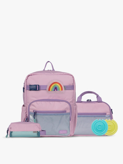 CALPAK Kids Collection Medium Kids Backpack Bundle in pink lavender Orchid Pink that includes Kids Lunch Bag, Kids Pencil Case, Rainbow Pluffy Bag Charm, and Set of 2 Ice Packs in a kid's room; BCKM2501-ORCHID-PINK view 1