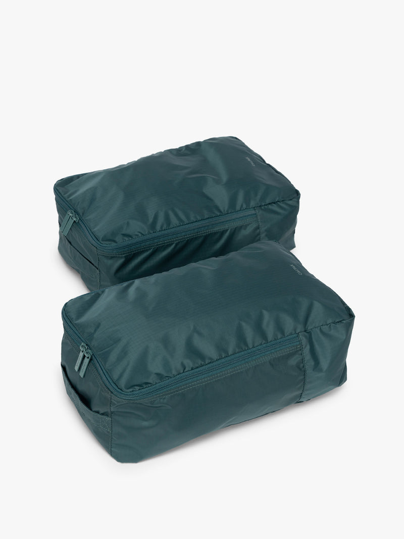 Closed zipper view of the dark green teal Kale rectangular CALPAK shoe cube with zippers and top handle shown on a plain background