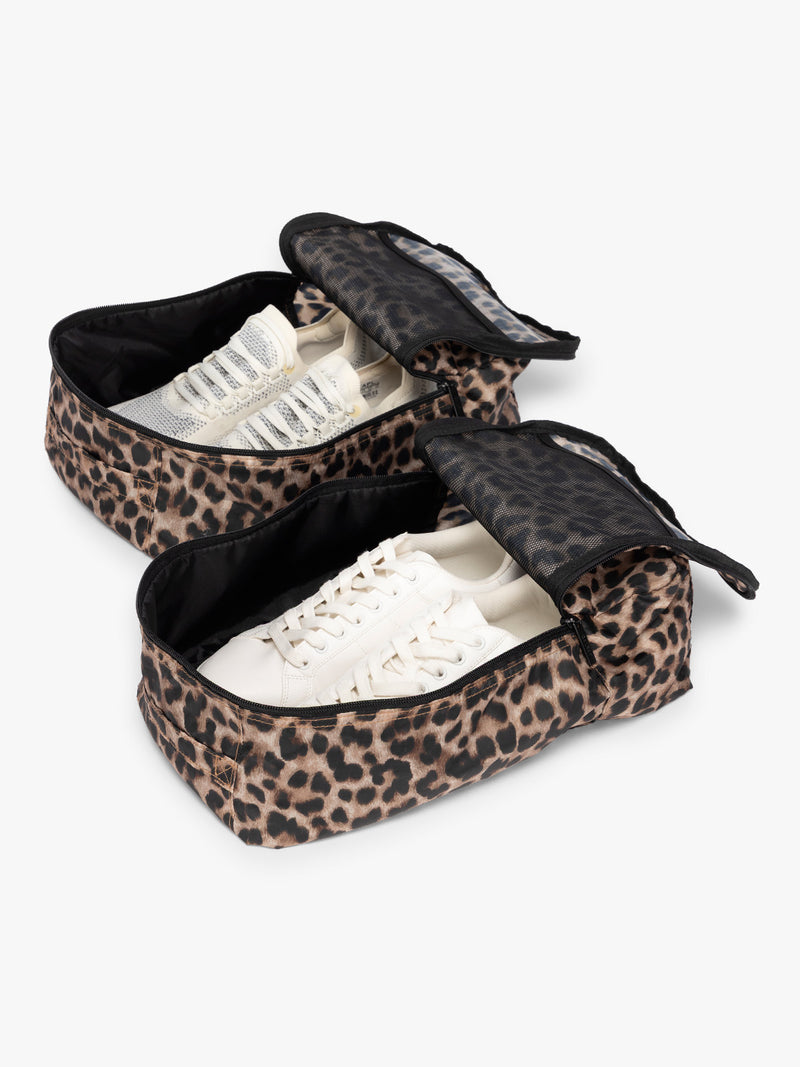 Opened view with shoes inside the Tan and black animal print Leopard rectangular CALPAK shoe cube with zippers and top handle shown on a plain background