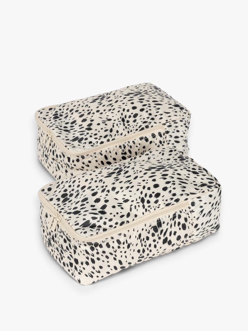 Closed view with zippers of the white and black animal print Snow Leopard rectangular CALPAK shoe cube with zippers and top handle shown on a plain background