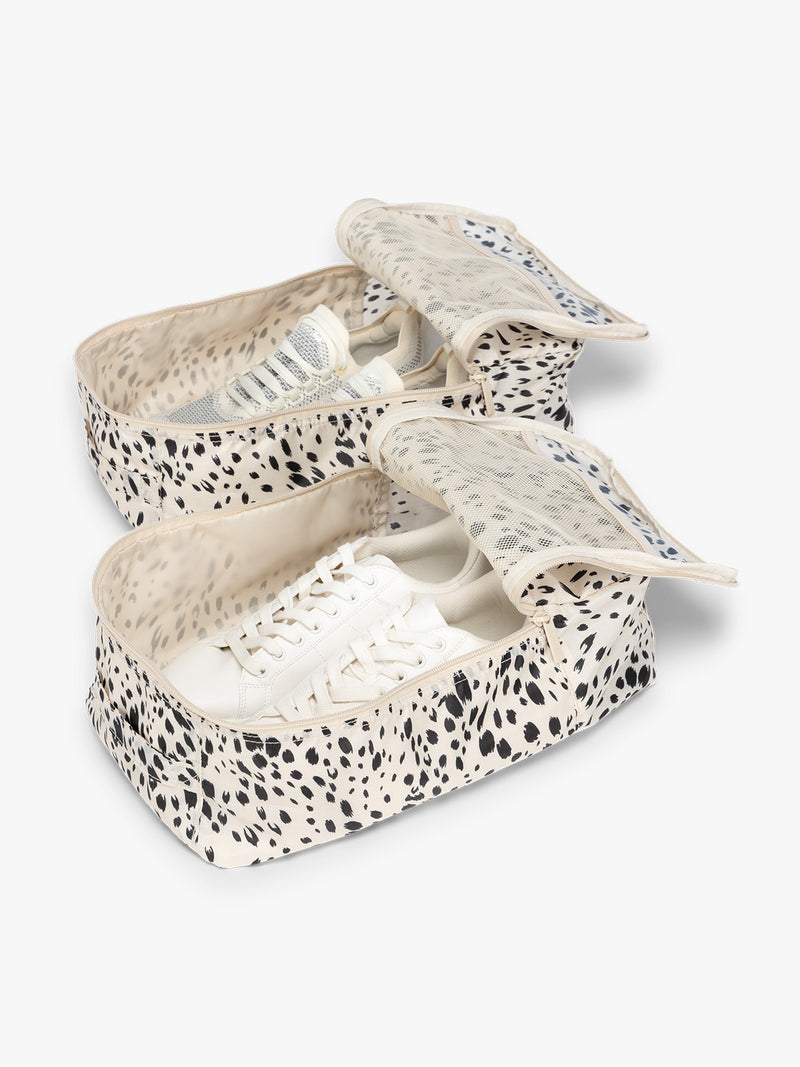 Opened view with shoes inside the White and black animal print Snow Leopard rectangular CALPAK shoe cube with zippers and top handle shown on a plain background