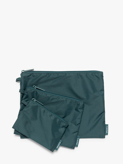 Three dark green teal Kale CALPAK Compakt Zippered pouches of different sizes, arranged in a fan-like layout on a clean white background; KZB2001-KALE view 1