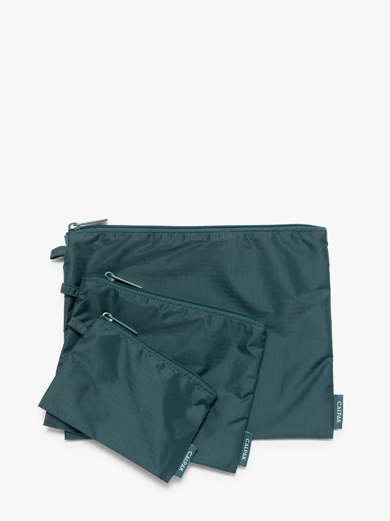 Three dark green teal Kale CALPAK Compakt Zippered pouches of different sizes, arranged in a fan-like layout on a clean white background