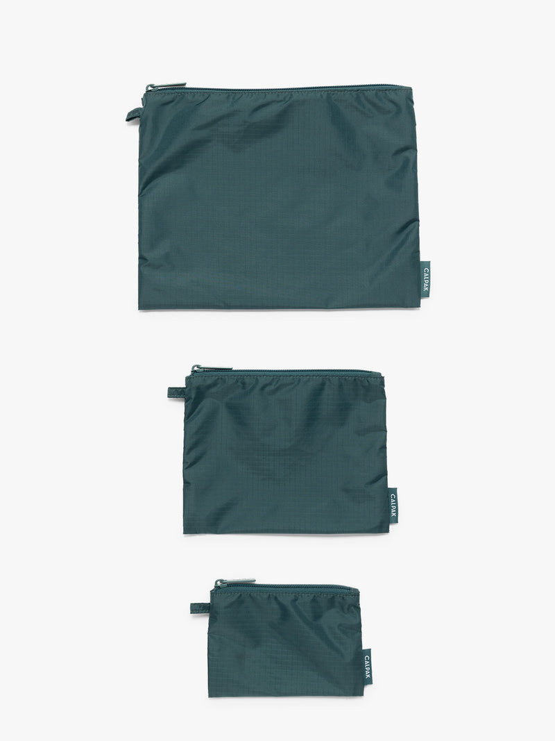 Flat lay of dark green teal Kale CALPAK Compakt Zippered pouches of different sizes, on a clean white background