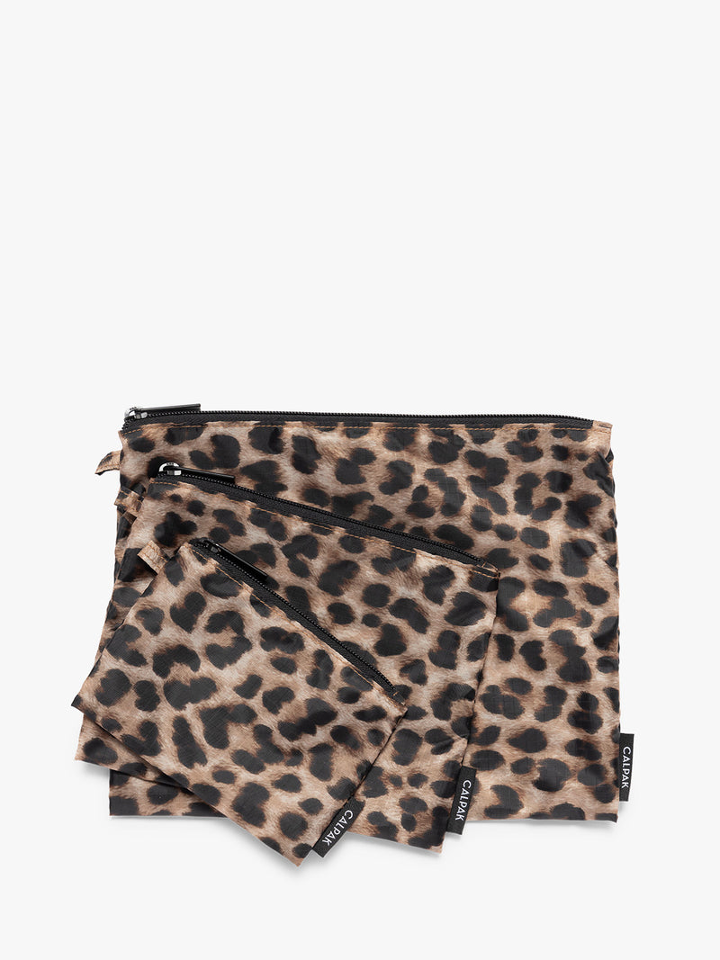 Three tan and black animal print Leopard CALPAK Compakt Zippered pouches of different sizes, arranged in a fan-like layout on a clean white background
