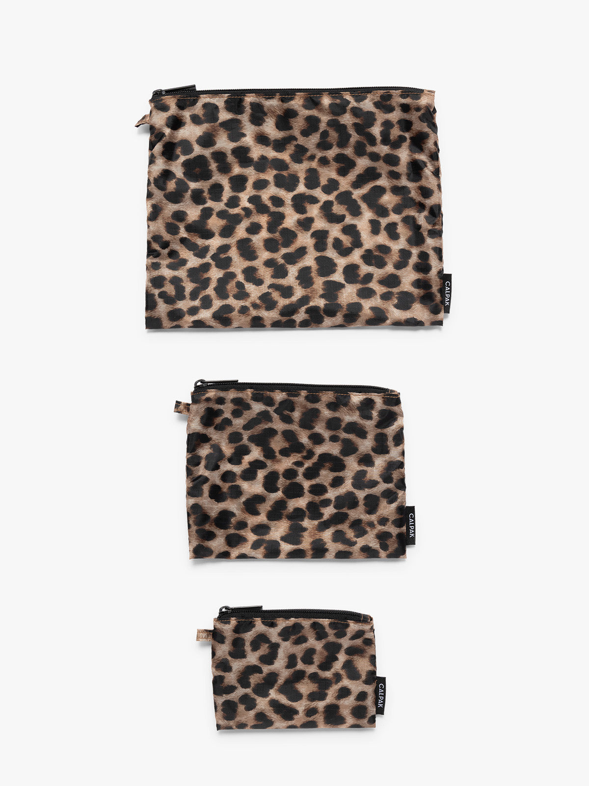 Flat lay of tan and black animal print Snow Leopard CALPAK Compakt Zippered pouches of different sizes, on a clean white background; KZB2001-LEOPARD