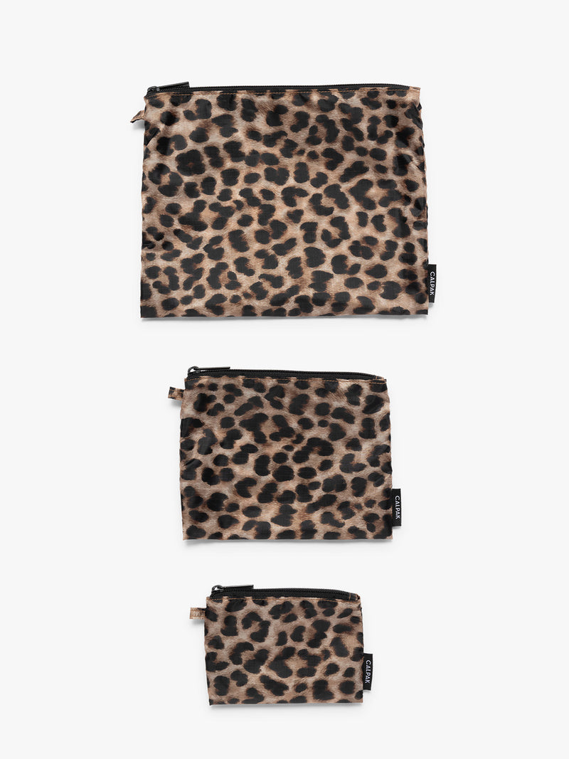 Flat lay of tan and black animal print Snow Leopard CALPAK Compakt Zippered pouches of different sizes, on a clean white background