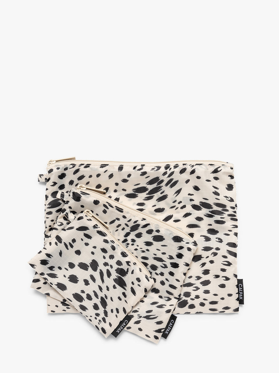 Three white and black animal print Snow Leopard CALPAK Compakt Zippered pouches of different sizes, arranged in a fan-like layout on a clean white background; KZB2001-SNOW-LEOPARD