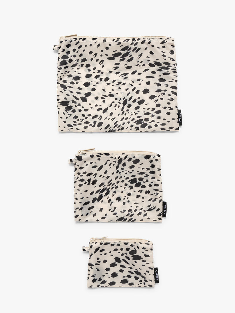 Flat lay of white and black animal print Snow Leopard CALPAK Compakt Zippered pouches of different sizes, on a clean white background