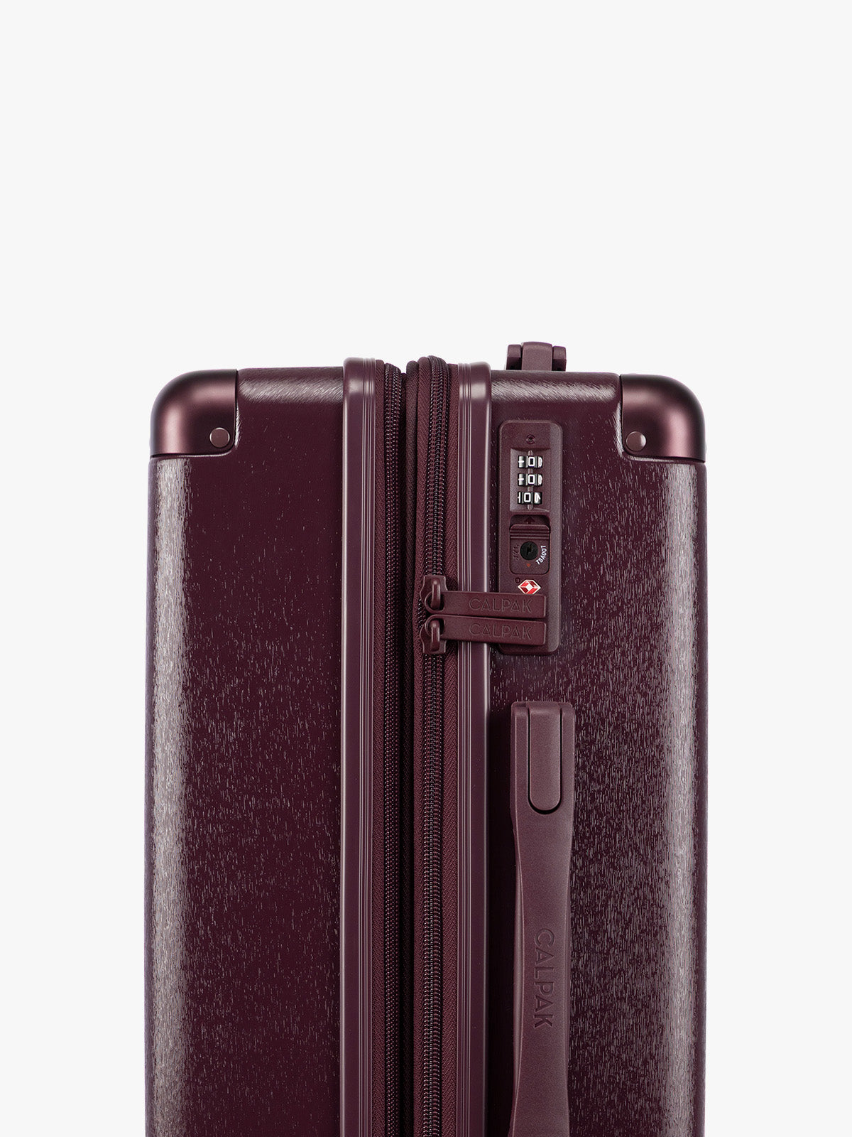 Close up TSA lock view from the CALPAK Dark Cherry burgundy Ambeur Carry On  hard-shell suitcase with a telescoping handle extended, shown from the front against a plain white background; LAM1020-DARK-CHERRY