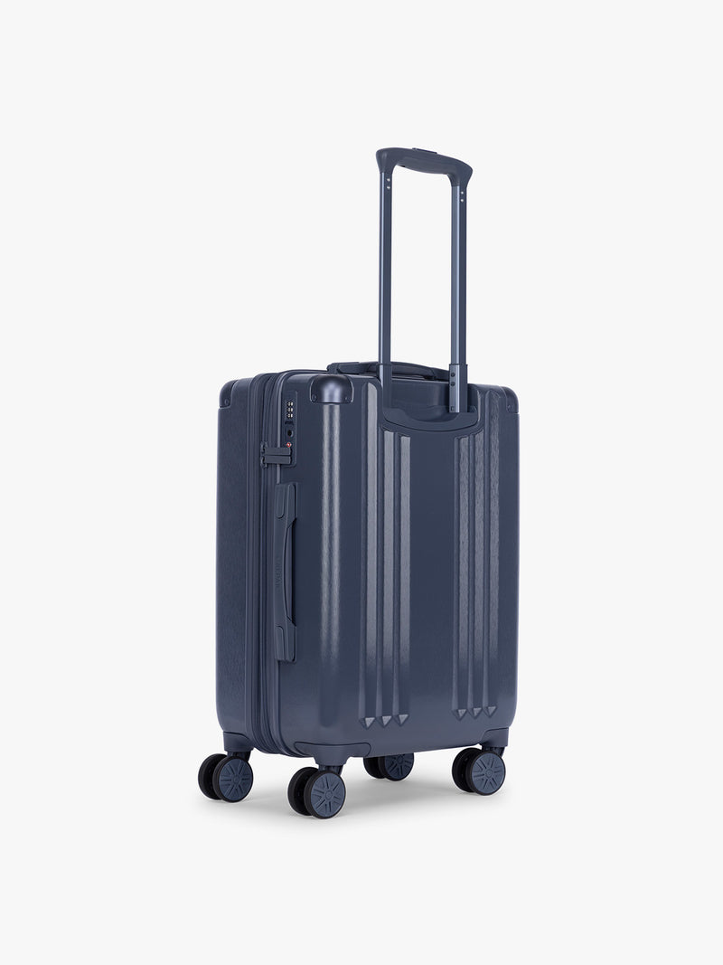 Back view of Model holding CALPAK Ambeur Carry On Luggage in dark blue metallic Indigo