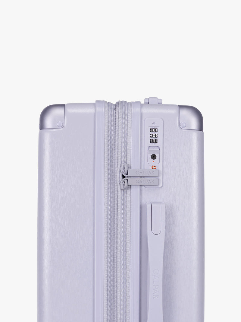 Side TSA approved lock of CALPAK Two Piece Amber Luggage Set in light purple lavender with handles and spinner wheels on a white background
