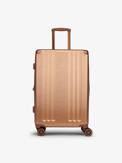 Studio product shot of front-facing CALPAK Ambeur medium 26-inch lightweight hardshell luggage with 360 spinner wheels in copper; model LAM1024-COPPER