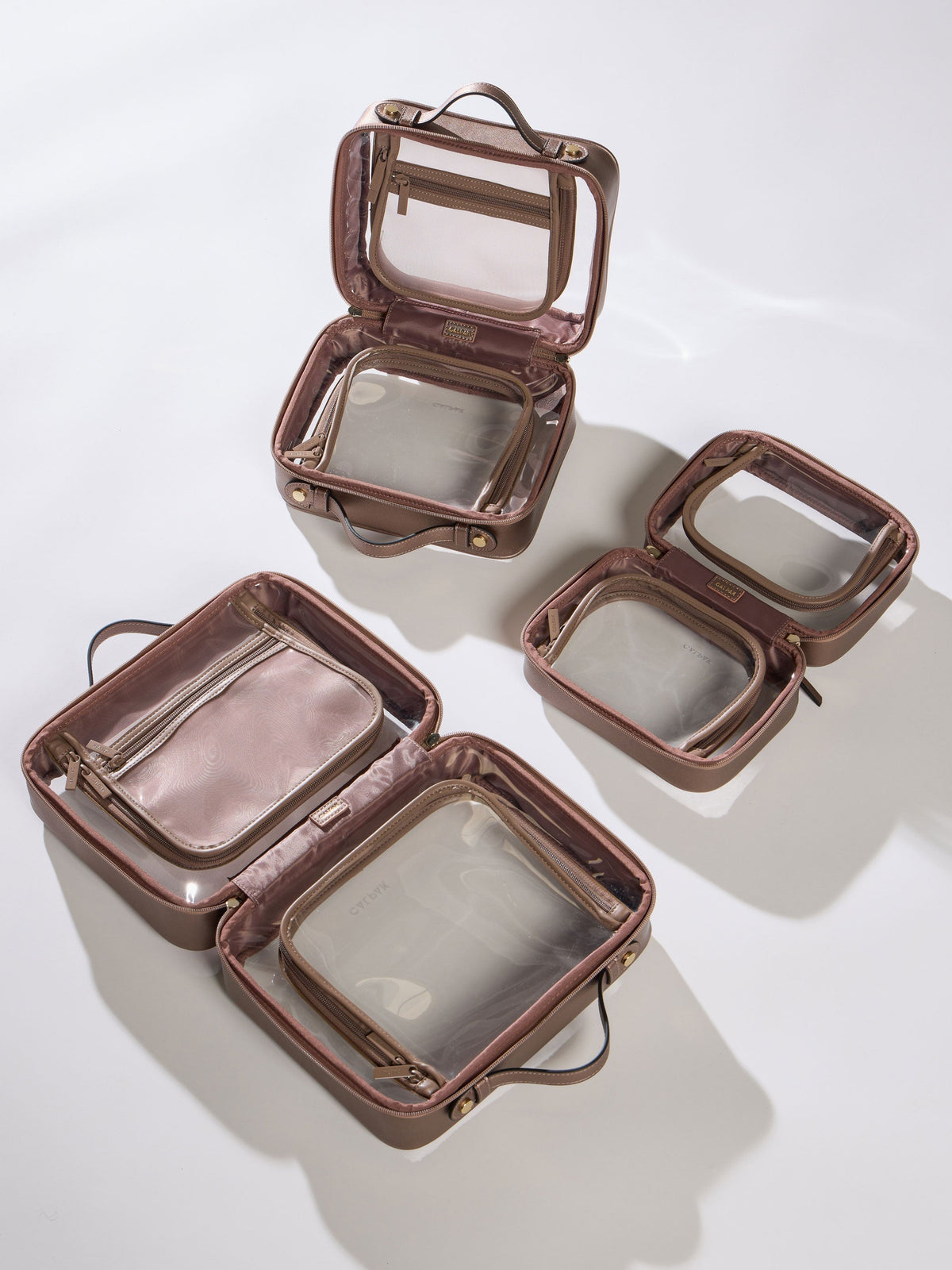 CALPAK Large Clear Cosmetic Case, Medium Clear Cosmetic Case, and Small Clear Cosmetic Case in bronze; CCC2001-BRONZE